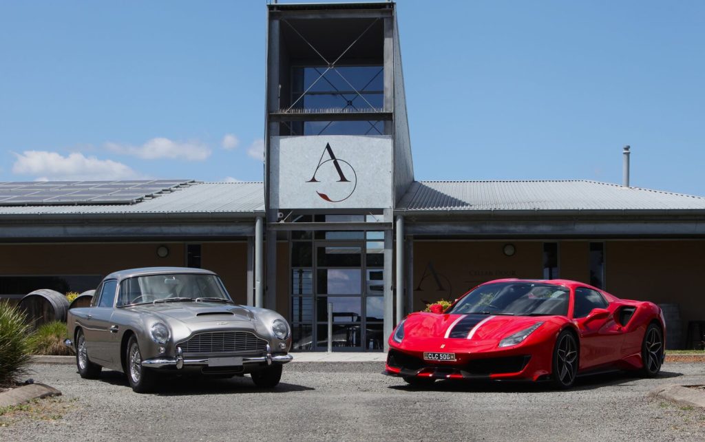 Image shows two classic cars - the Aston Martin DB5 and Ferrari 488 Pista at Adina Vineyard
