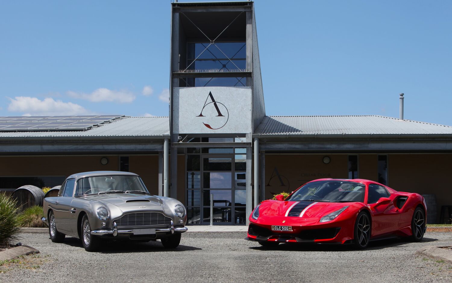 Image shows two classic cars - the Aston Martin DB5 and Ferrari 488 Pista at Adina Vineyard